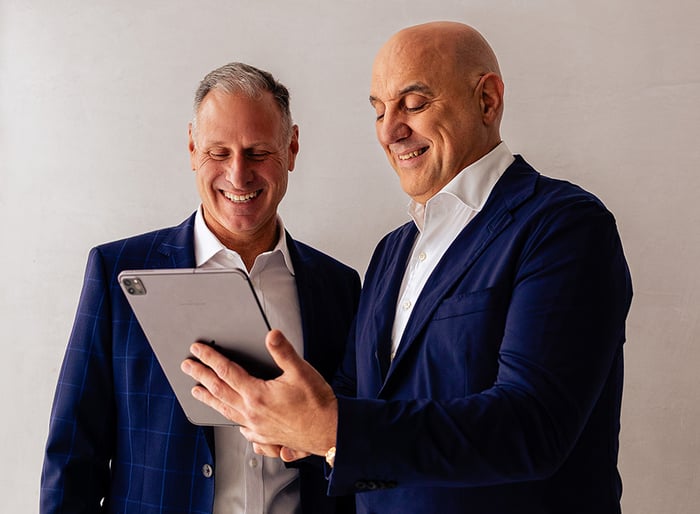 Ezderm Founder, Srdjan Prodanovich, and Ezderm CEO, Todd Hicks, are smiling and looking at an iPad.