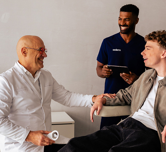Dermatologist in an exam room with a patient and a medical assistant