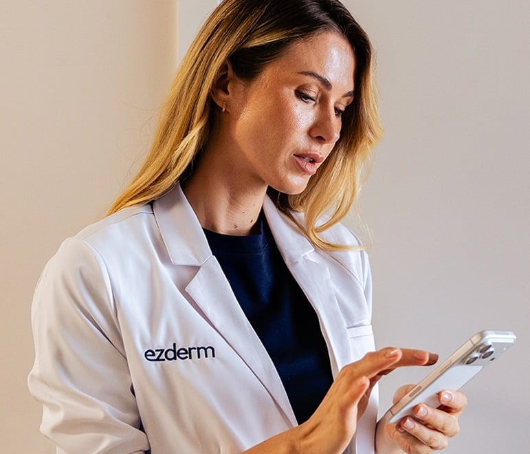 Clinician in an Ezderm coat tapping on an iPhone