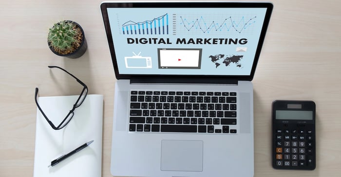 A photo of a laptop showing a screen with charts and graphs and a title that says digital marketing.