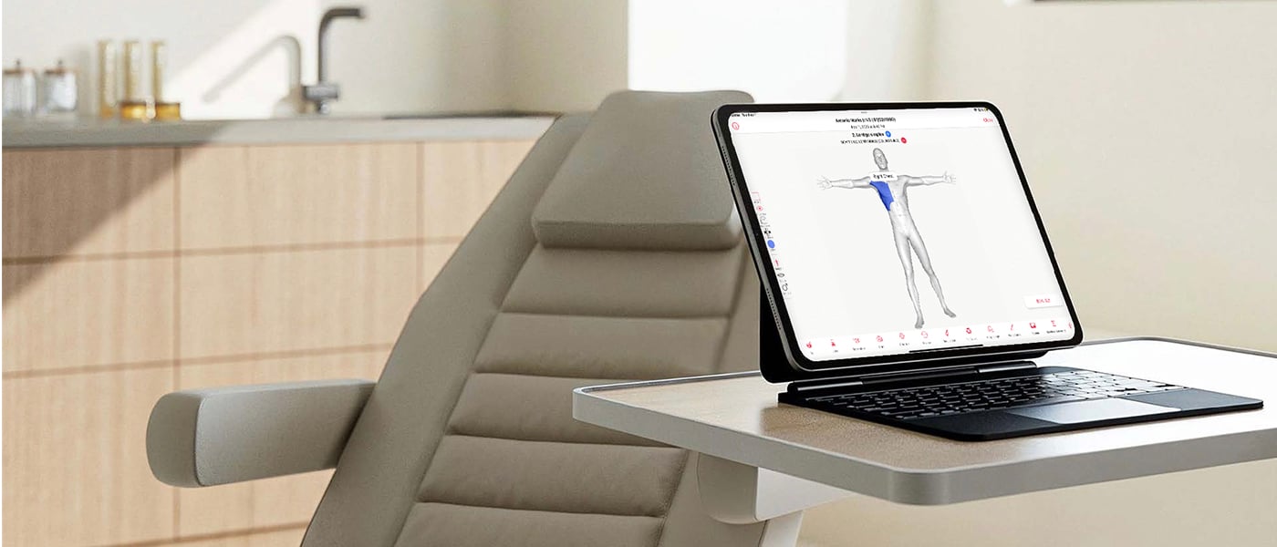 Modern dermatology exam room with a reclining exam chair and attached tray holding an iPad. The iPad displays a 3D body map used for digital skin charting and documentation.
